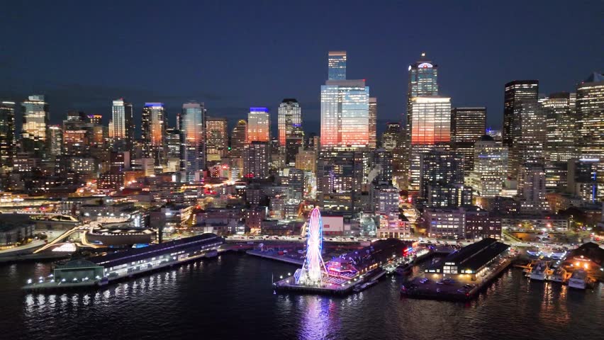 A breathtaking aerial night view of downtown Seattle, Washington, showcasing the illuminated skyline and iconic skyscrapers. Glowing Seattle Great Wheel. Seattle at night. Top cinematic aerial view