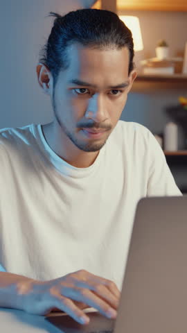 Vertical Screen : Freelance asian couple man and woman in casual focus work in laptop computer at night wife take a rest feel relax wear headphones play music on smartphone dance on couch at home.