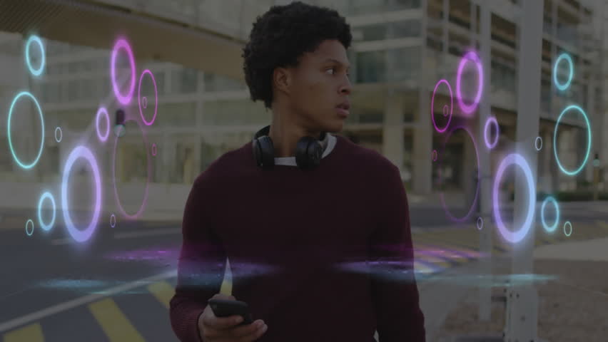 Man holding smartphone wearing headphones at urban intersection, neon rings illustrating AR tech. City, technology, futurism, electronics, innovation, lifestyle, vibrant