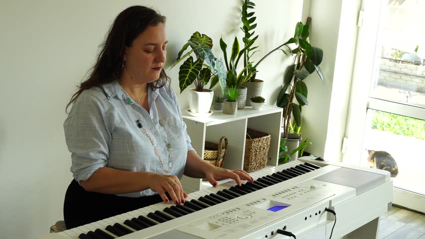 Middle age woman plays on piano and sings songs