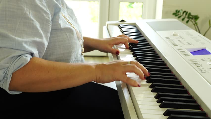 Middle age woman plays on piano and sings songs