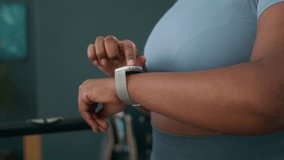 Slowmo of plus-sized Black woman in athletic wear checking her smartwatch after completing her treadmill session, tracking her workout data and fitness goals - Powered by Shutterstock - Get 15% off with code: PIKWIZARD15