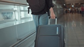 Rear view - Male traveler walking with luggage or suitcase at the modern airport terminal, man on way to flight boarding gate, Ready for travel or vacation journey. - Powered by Shutterstock - Get 15% off with code: PIKWIZARD15
