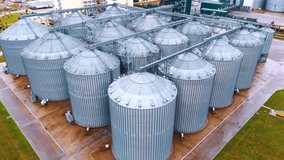 Approaching the rows of metal tanks for grain storage. Elevators at the modern agricultural enterprise. Aerial view. - Powered by Shutterstock - Get 15% off with code: PIKWIZARD15