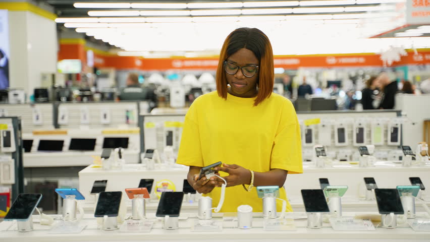 African American woman choosing a smartphone in tech store