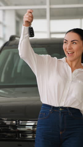 Smiling woman holding car keys at dealership