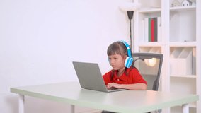 Asian girl studying online using laptop and wearing headphones sitting at desk in her room with bookshelf in background, homeschooling concept - Powered by Shutterstock - Get 15% off with code: PIKWIZARD15