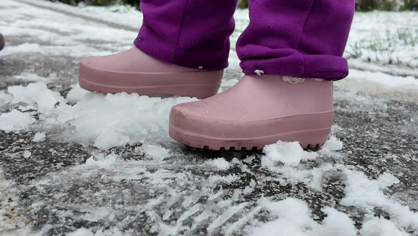 Children enjoy snowy weather while wearing colorful boots outdoors