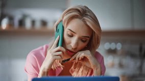 Relaxed woman speaking smartphone resting in domestic atmosphere portrait. Worried lady communicating by cellphone at home kitchen. Calm blonde holding pen discussing news in mobile phone conversation - Powered by Shutterstock - Get 15% off with code: PIKWIZARD15