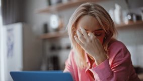Exhausted blonde rubbing neck experiencing fatigue at kitchen portrait. Frustrated businesswoman working laptop closeup. Overworked woman tired from deadline sitting at light apartment interior alone  - Powered by Shutterstock - Get 15% off with code: PIKWIZARD15