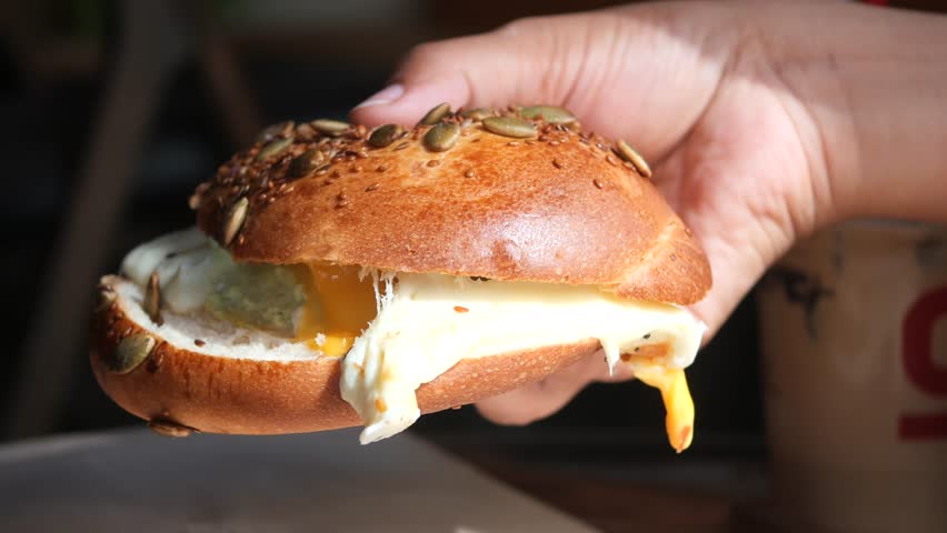 Freshly made bagel sandwich with egg and cheese in hand