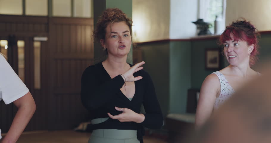 Women, trainer and yoga with meditation, fitness and conversation with exercise, wellness and peace retreat. People, girls or yogi on the floor, speaking or explain posture with health, group or calm