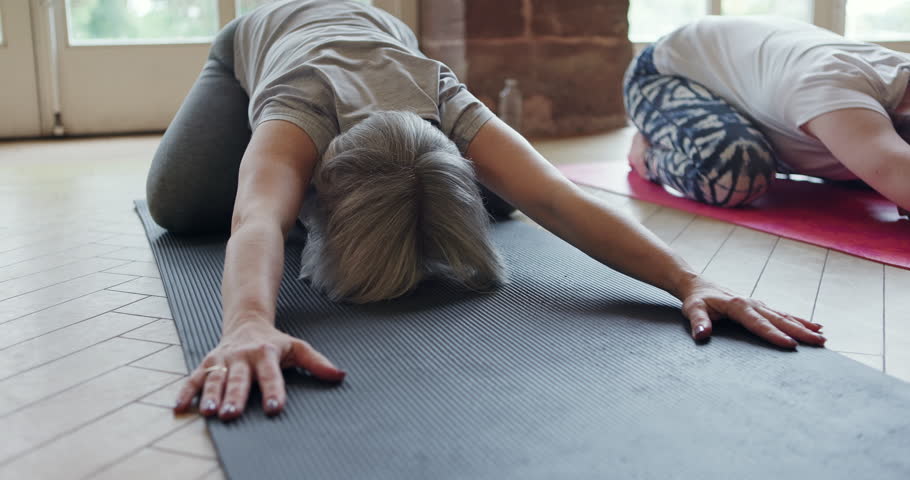 Class, yoga or people in child pose stretching for a healthy spine, body balance or wellness. Floor, fitness or calm women in exercise, pilates or group together for flexibility in a zen studio