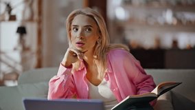 Serious student studying at home couch writing notebook closeup. Focused blonde woman making notes in copybook listening online webinar on laptop. Relaxed young girl watching educational video on sofa - Powered by Shutterstock - Get 15% off with code: PIKWIZARD15