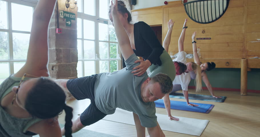 Instructor, help and people stretching in yoga class for fitness, health and wellness. Men and women group at zen club for meditation, workout and healing or relax with balance, exercise and pilates