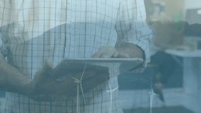 Man holding tablet sharing finance chart overlay in modern office, showing wind turbine icons. Technology, innovation, sustainability, collaboration, data analysis, corporate, modern - Powered by Shutterstock - Get 15% off with code: PIKWIZARD15