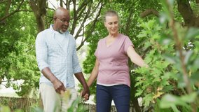 Senior couple walking through lush garden, displaying floating heart icons for health. Romance, love, companionship, nature, serenity, affection, outdoor - Powered by Shutterstock - Get 15% off with code: PIKWIZARD15