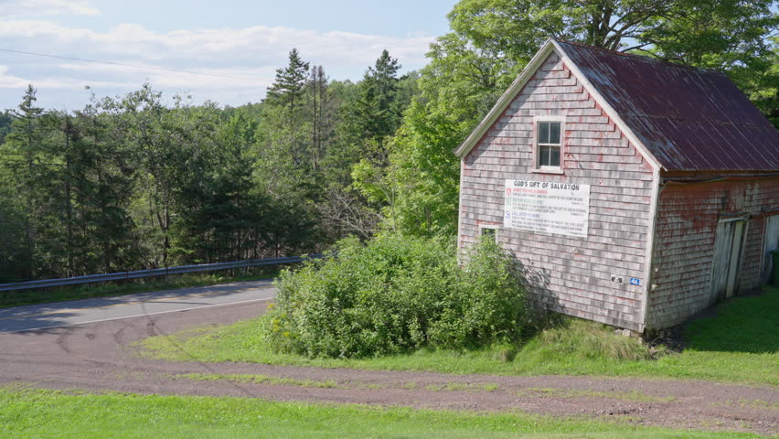 Old barn with Christian salvation message stands near quiet country road