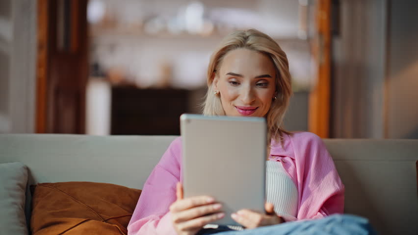 Interested woman swiping tablet social media on home couch closeup. Relaxed businesswoman reading work email sitting apartment living room. Surprised girl surfing internet online at computer indoors