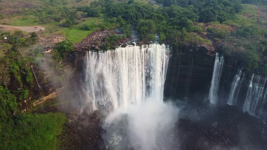 a stunning aerial shot of a massive waterfall plunging from a cliff with dense green vegetation above it Angola