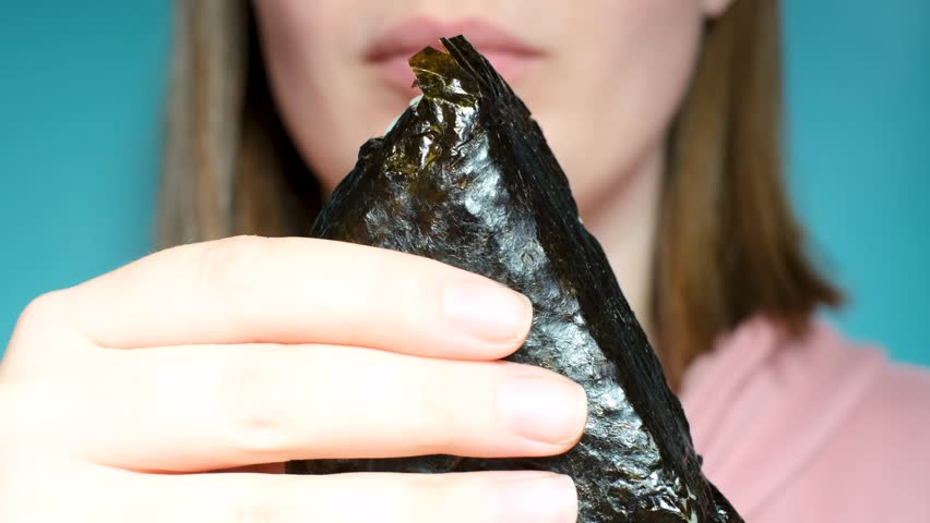 Young woman holding korean samgak close-up on blue background.
