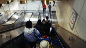 People descend an escalator in a Hong Kong metro station. The scene captures urban life in motion, showcasing commuters in a busy environment. Digital signage and tiled walls add context - Powered by Shutterstock - Get 15% off with code: PIKWIZARD15