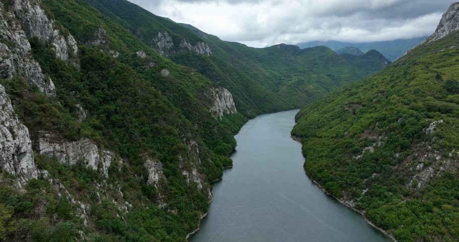 Fjord landscape by Lake Koman and green hills in Albania, forward aerial