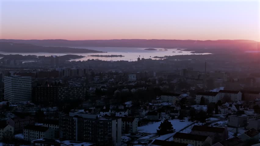 Downtown Oslofjord Olso city Norway Norge aerial drone view inner coastline Hovedøya Lindøya islands Norwegian arctic vibrant pink purple hue sunset apartment buildings cityscape parallax circle right