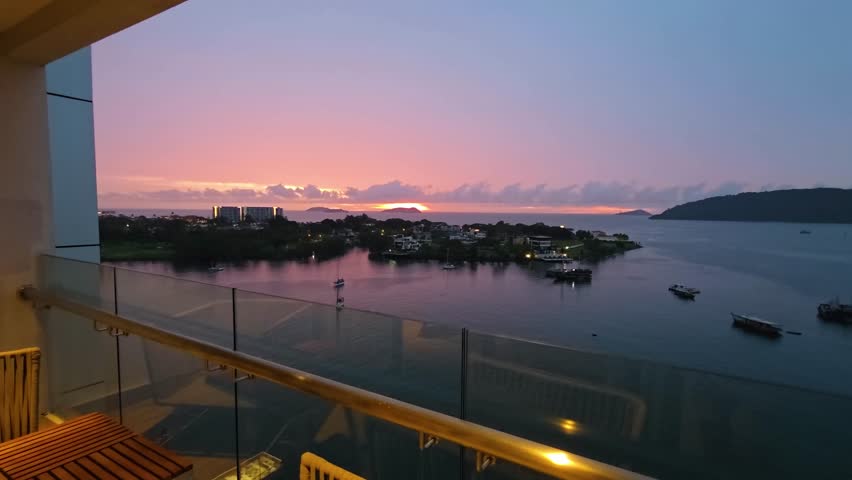 Aerial-style view from Marriott Hotel balcony in Kota Kinabalu, Malaysia, capturing a vivid sunset over calm sea with boats near Sutera Harbor in a peaceful tropical coastal setting