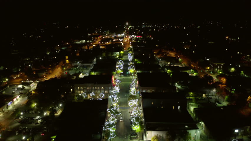 Aerial Tilt Down Shot Of Cars Moving On Road Amidst Illuminated Trees In Residential Town At Night - Moscow, Idaho