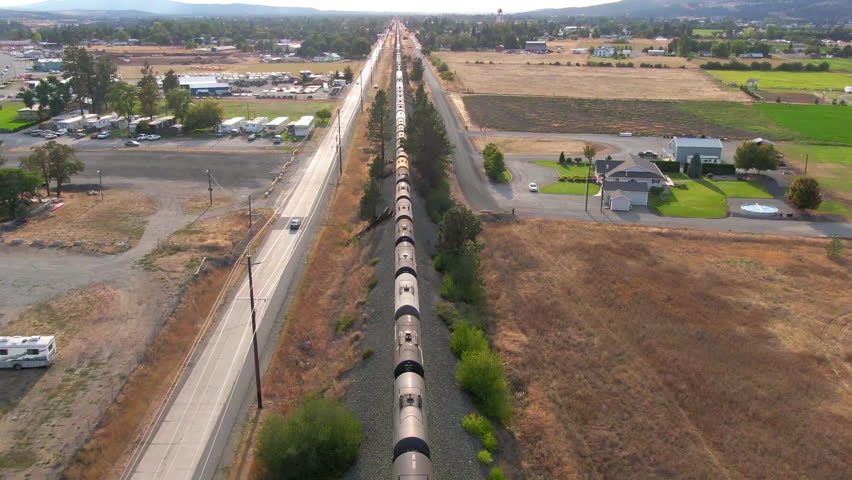 Aerial Tilt Down Shot Of Railway Moving On Track In Residential Town During Sunny Day - Post Falls, Idaho