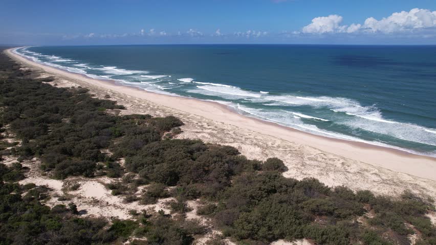 Pristine Beach On South Stradbroke Island With Rolling Waves And Coastal Scrub Along Shoreline. Queensland, Australia. wide aerial shot