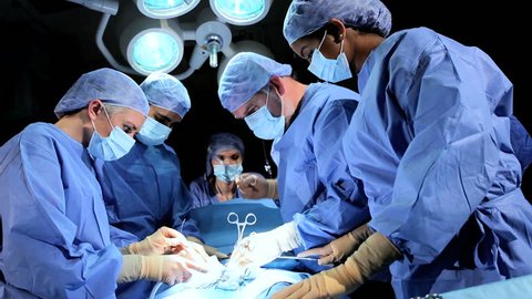 Multi ethnic medical team performing operation in hospital operating theater