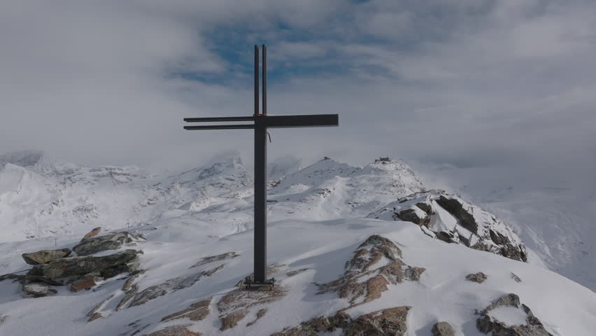 Aerial Panning Shot Of Summit Cross On Mountain Peak With Snow Against Sky - Zermatt, Switzerland