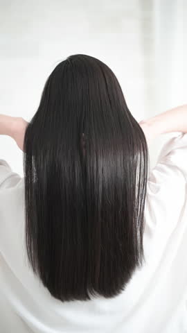 Beautiful cuticles of long straight shiny black hair. Hair care and other images of hair. Back view, face not shown. Vertical animation of shaking hair.