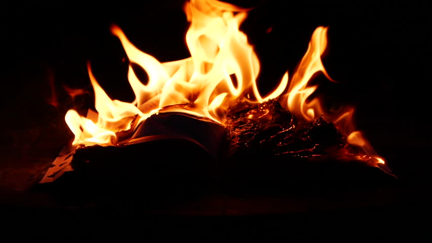 Slow motion of open book burning in fire, fire flame, burning old paper on ground on dark background