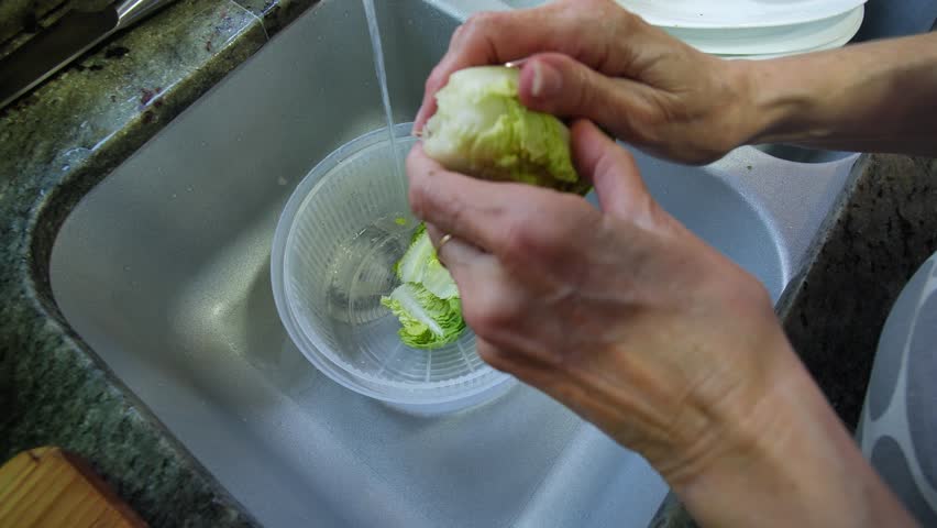 Housewife washing lettuce in her kitchen. High quality 4k footage