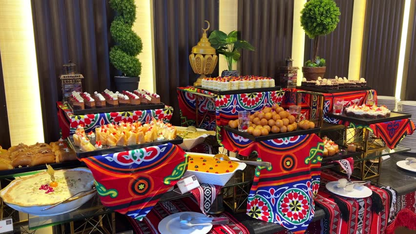 Festive 4K shot of a traditional dessert buffet featuring Middle Eastern sweets, Ramadan lanterns, and vibrant Arabic textiles. Great for hospitality, Ramadan promos, cultural food features.