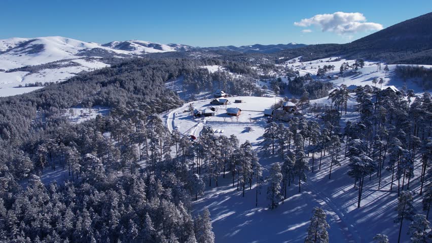 Aerial View of Hilltop Houses and Snow Capped Landscape, Forest and Wilderness on Sunny Winter Day