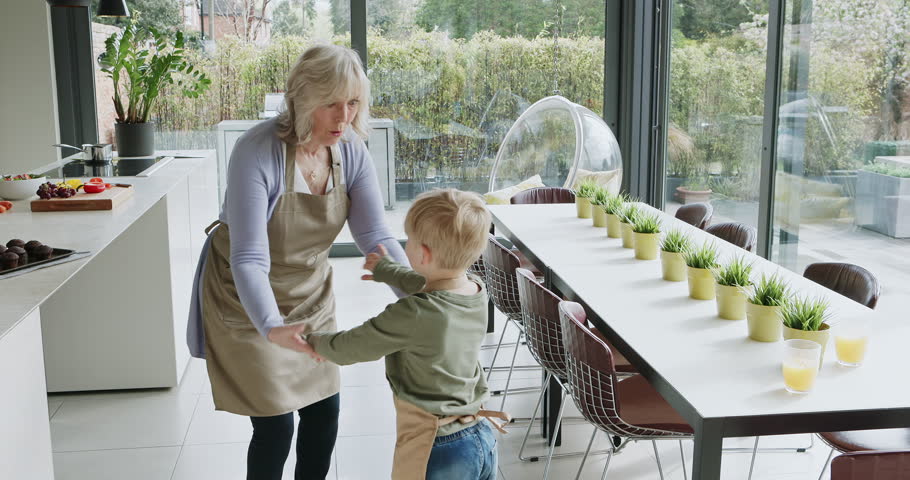 Kitchen, dance or happy grandma with a child playing or laughing with joy in family home together. Fun grandmother, kid baking or old woman dancing, holding hands or bonding in retirement or house