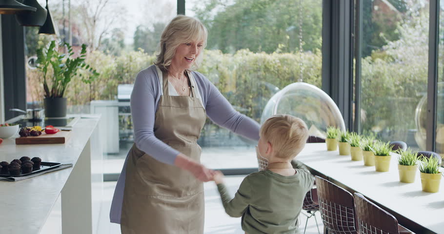 Kitchen, dancing or happy grandma with a child playing or laughing with joy in family home together. Cooking breakfast, kid or fun grandmother baking, bonding or holding hands to dance in retirement
