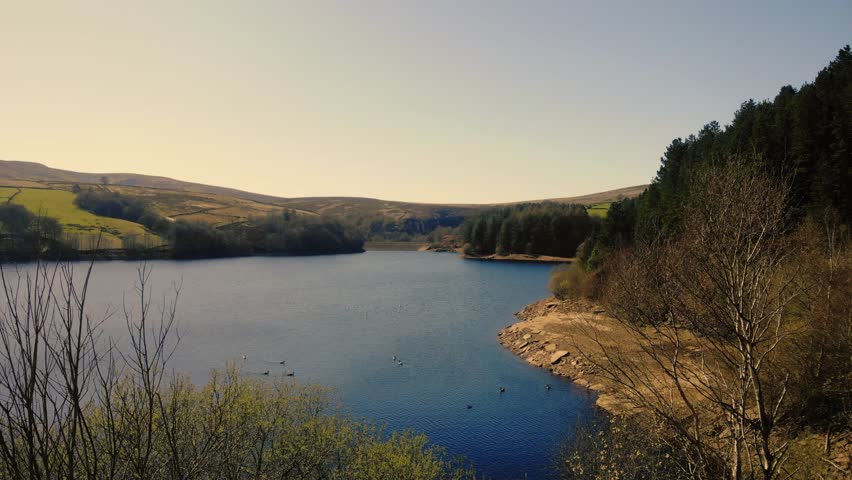 Lake and farmland in Peak District National Park blue sky landscape wide 4k drone aerial selective focus