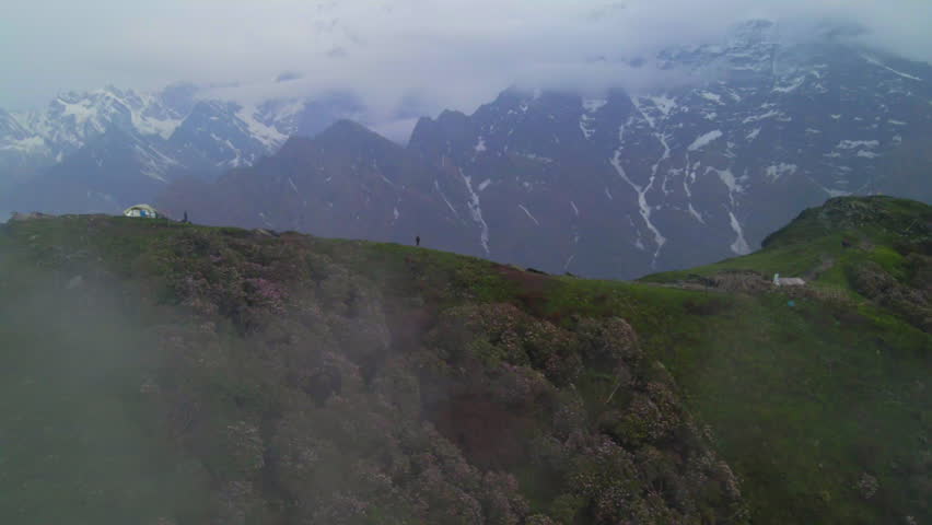 Aerial Forward Shot Of Man Standing On Top Of Mountain By Glacier Under Clouds - Himalayas, Nepal