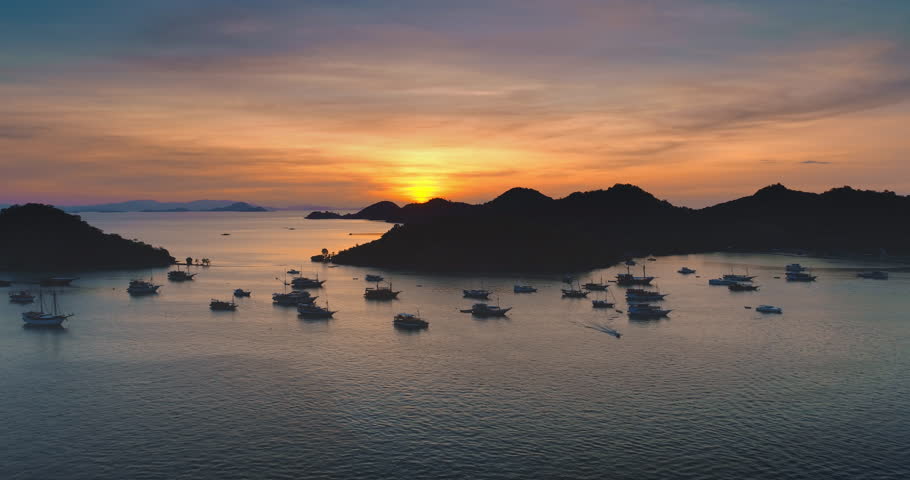 Many traditional boats floating near the coast of Ende, Flores Island, Indonesia during a breathtaking sunset illuminating the landscape with warm colors