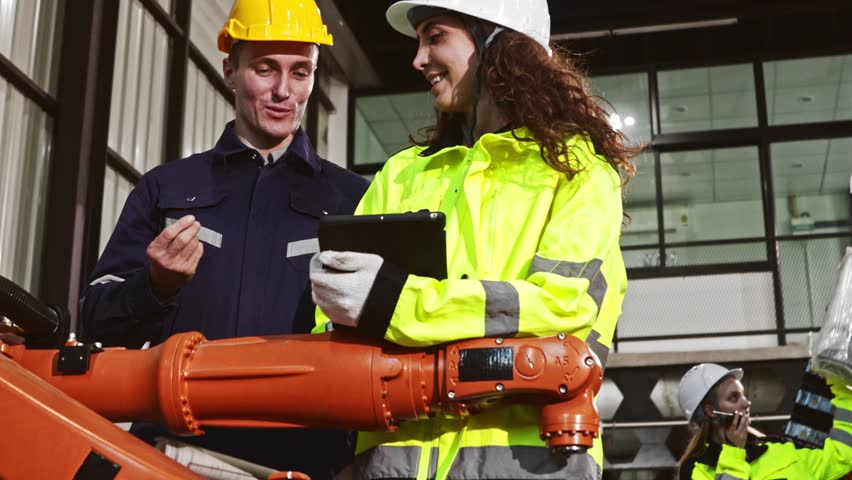 Male and female robot engineering team planning electricians brainstorming presenting knowledge checking electrical system blueprints new welding robots testing automatic electronics in the warehouse. - Powered by Shutterstock - Get 15% off with code: PIKWIZARD15