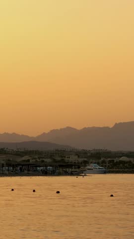 HURGHADA, EGYPT - OCTOBER 24, 2018: One of many quiet coves of the Red Sea, at sunset, at dusk. against the background of the outlines of mountains, palm trees