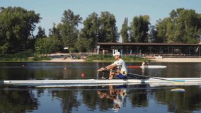 Rower solo training. Side view of young caucasian male rower, during a rowing practice, athlete sitting in a boat in the river Dnipro, rows through a calm water in autumn. 4k footage. Caucasian man tr - Powered by Shutterstock - Get 15% off with code: PIKWIZARD15