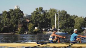 Rowing team training. Side view of 2 young caucasian male rowers, during a rowing practice, athlete sitting in a boat in the river Dnipro, rows through a calm water sunny day, autumn. 4k footage - Powered by Shutterstock - Get 15% off with code: PIKWIZARD15