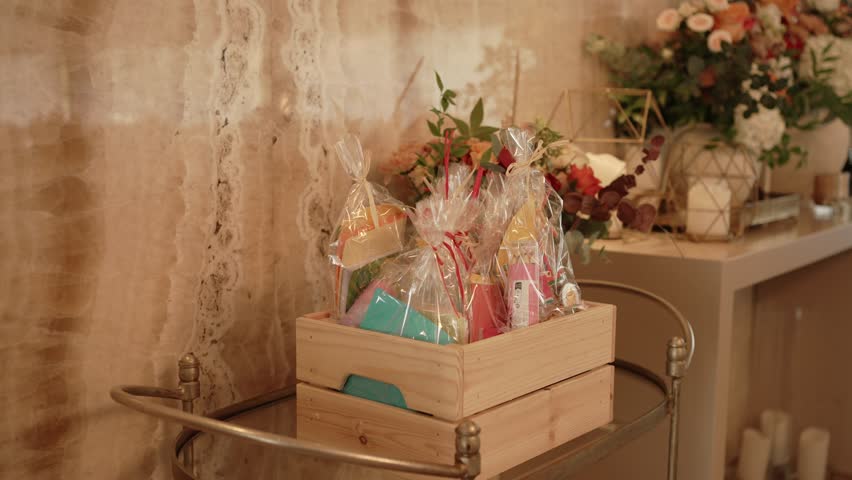 Colorful gift bags in clear wrap displayed in wooden box near floral wedding decor