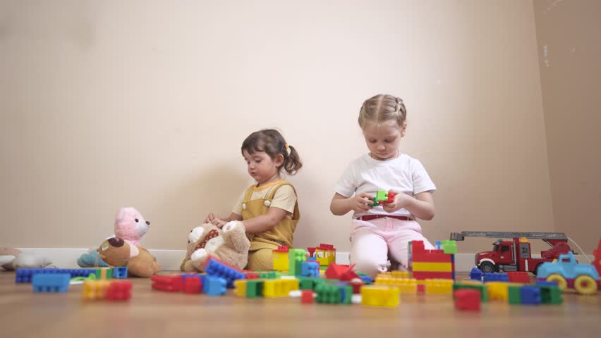 Two children playing with blocks. Group of children playing with toys in a kindergarten. Constructors build a kindergarten lifestyle together. Two kids engaging with building blocks.